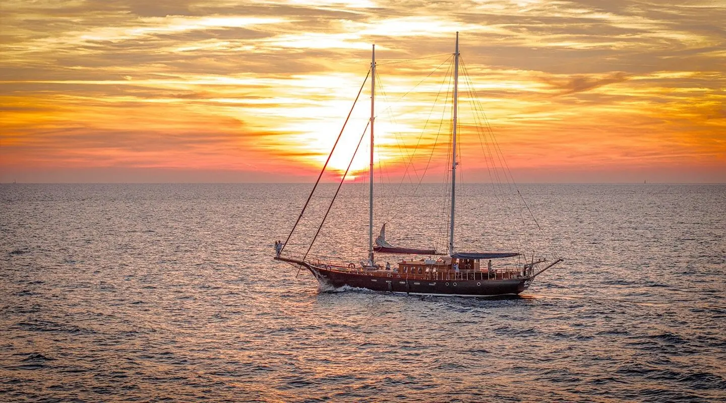 Gulet Smart Spirit sailing on calm sunset sea with orange sky