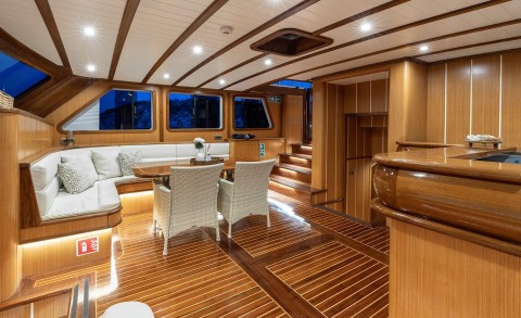 Inside a luxurious wooden yacht cabin with white seating and a wooden table