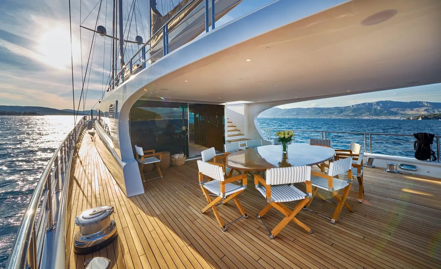 Aft deck on Acapella yacht with wooden floor, small table, chairs, and sea view