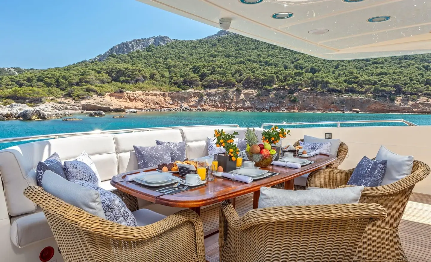 Yacht Divine aft deck with sun loungers, dining setup, and guests seated
