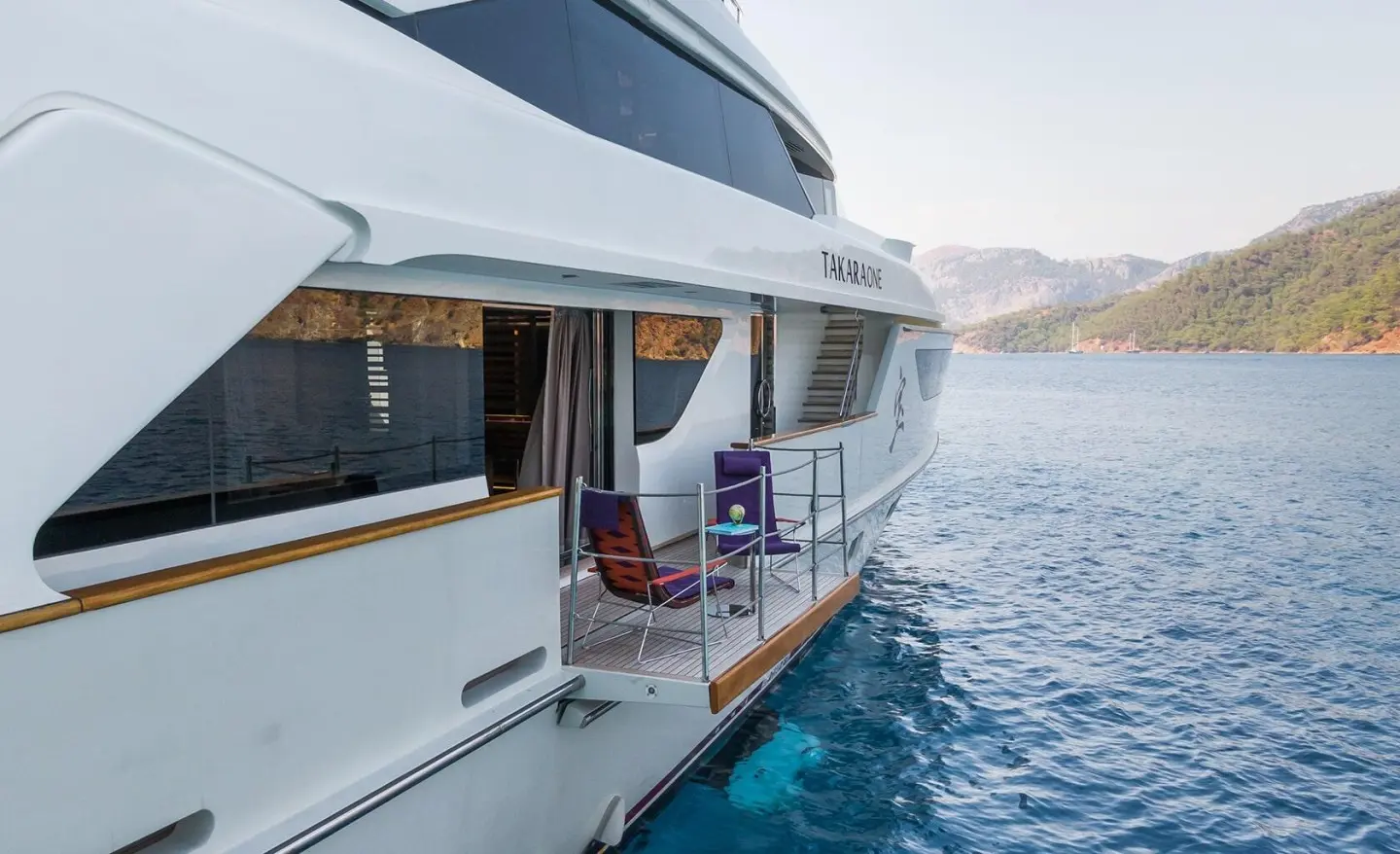 Takara One yacht deckside view with open doorway and seating by water