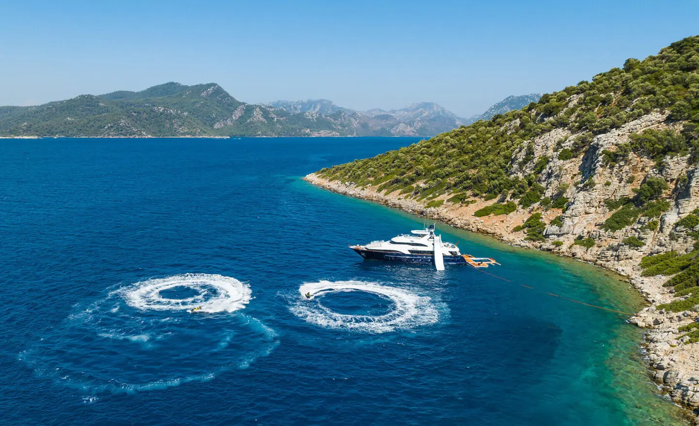 Amadea yacht anchored off sunseclude cliffs with circular wake rings nearby