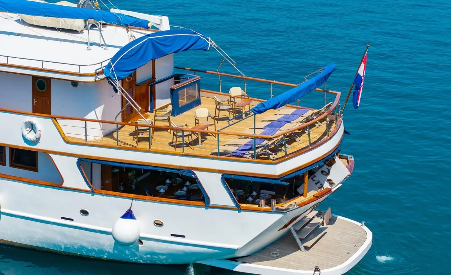 Sun deck of Mendula yacht with seating area and tables, blue sea surrounding