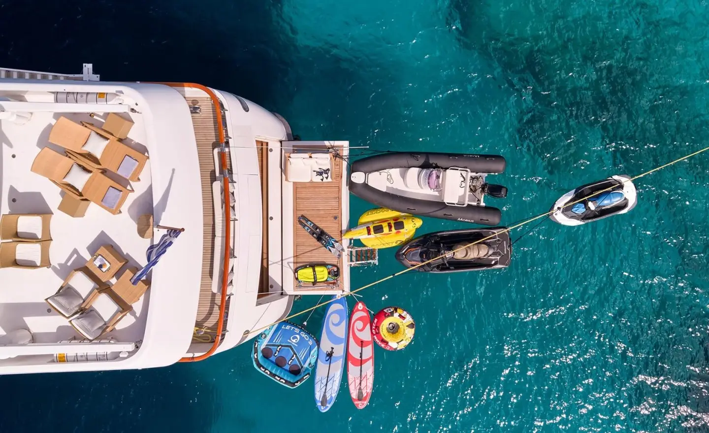 Bird's-eye view of Mobius yacht docked with water toys nearby in clear blue sea