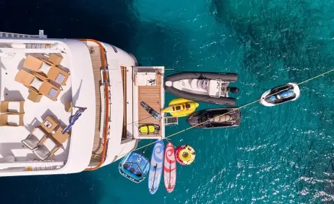 Bird's-eye view of Mobius yacht docked with water toys nearby in clear blue sea