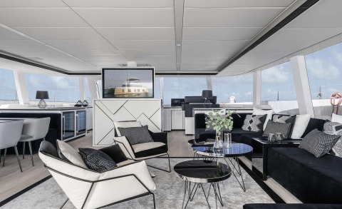 Luxurious salon on Above & Beyond yacht interior with quartz tables and monochrome seating