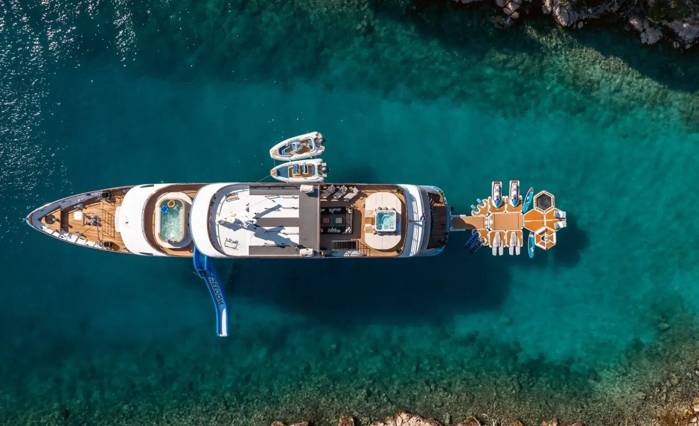 Aerial view of a white motor yacht named Freedom docked in clear blue water