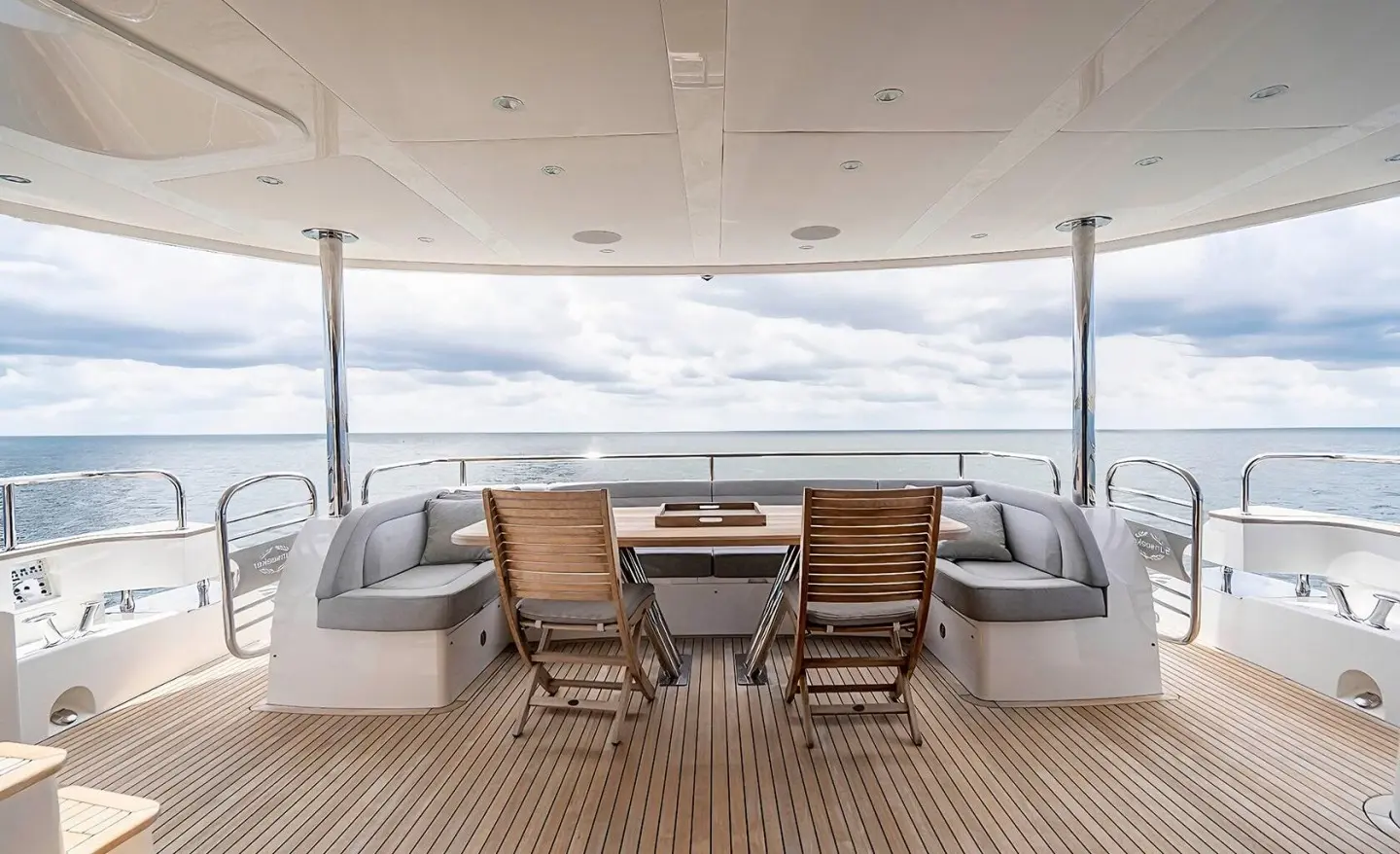 Upper deck with wood table and chairs, outdoor seating facing the sea