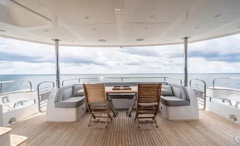 Upper deck with wood table and chairs, outdoor seating facing the sea