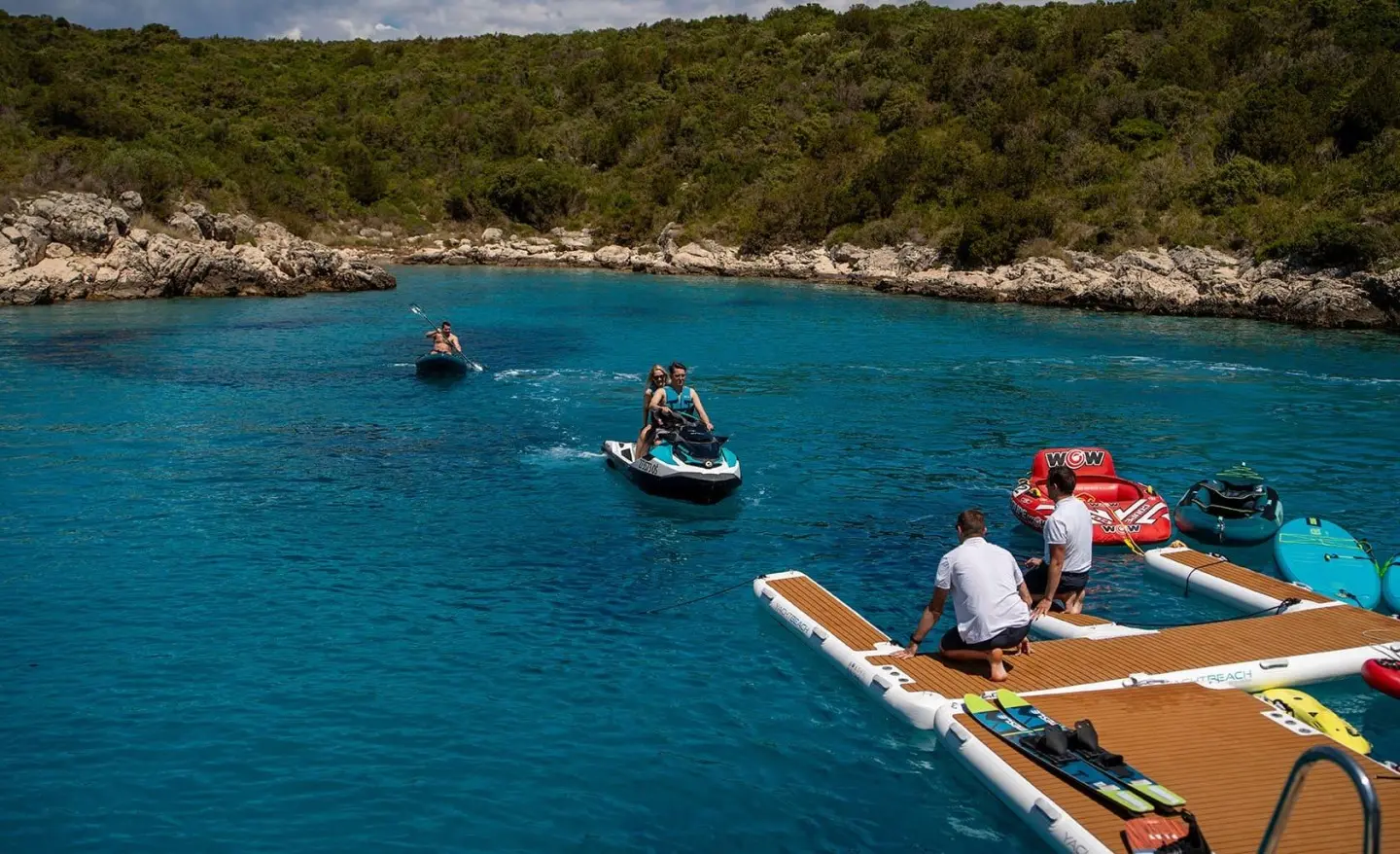 Yacht Anima Maris anchored near rocky coastline with water sports boats nearby
