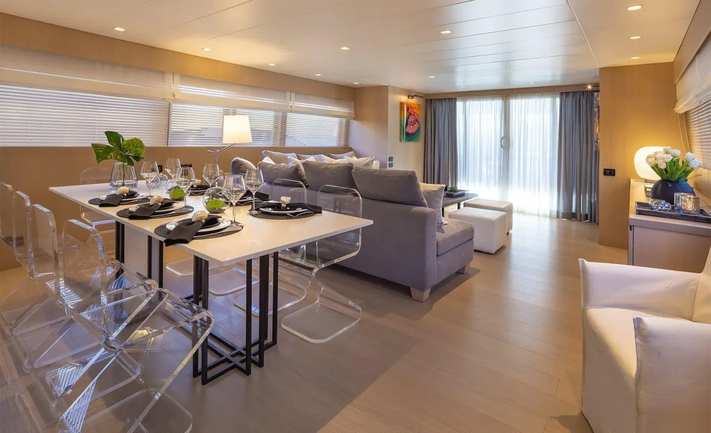 Dining area on a yacht with a large L-shaped couch, table settings, and windows