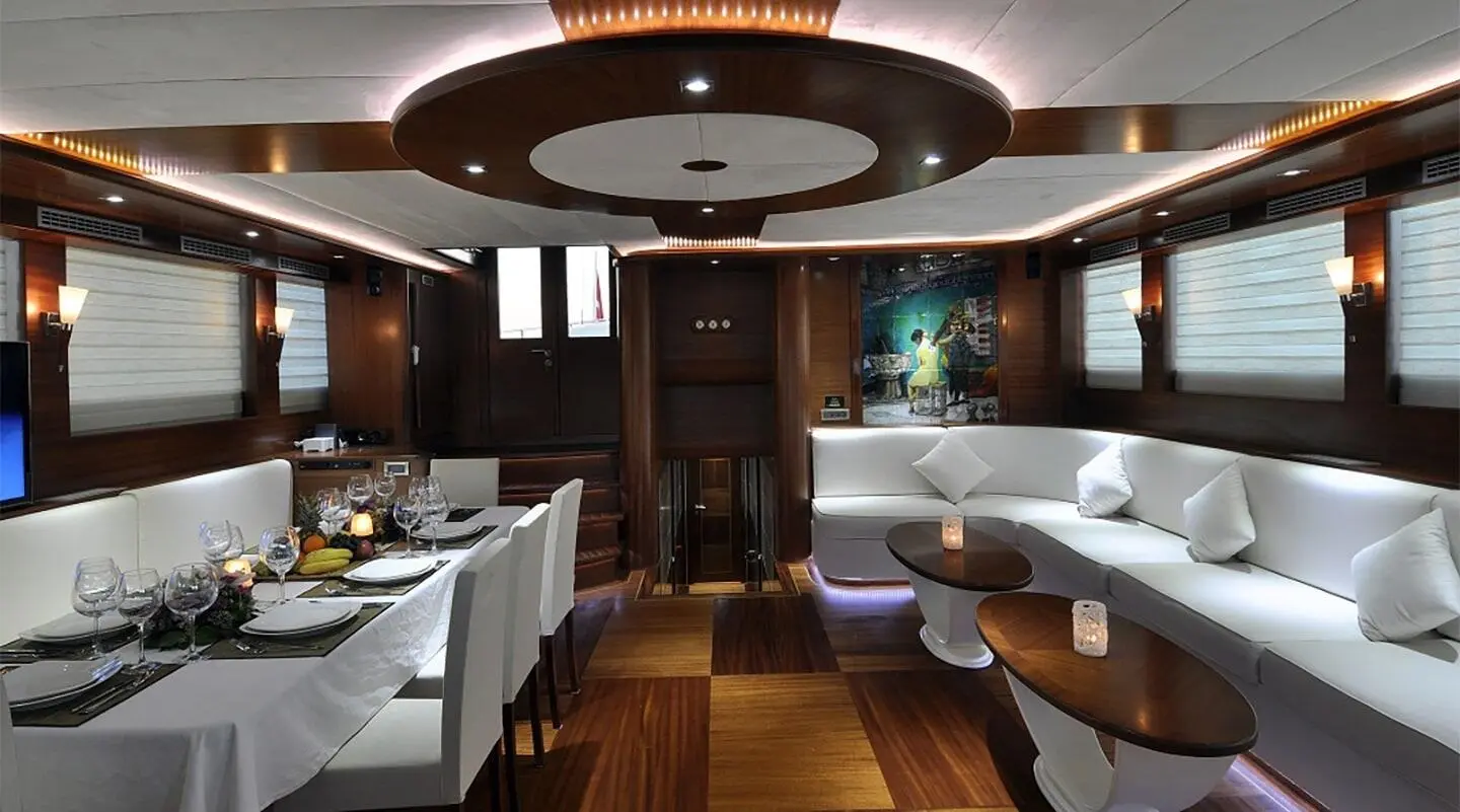 Interior of a luxurious yacht with white seating, wooden floor, and ambient lighting
