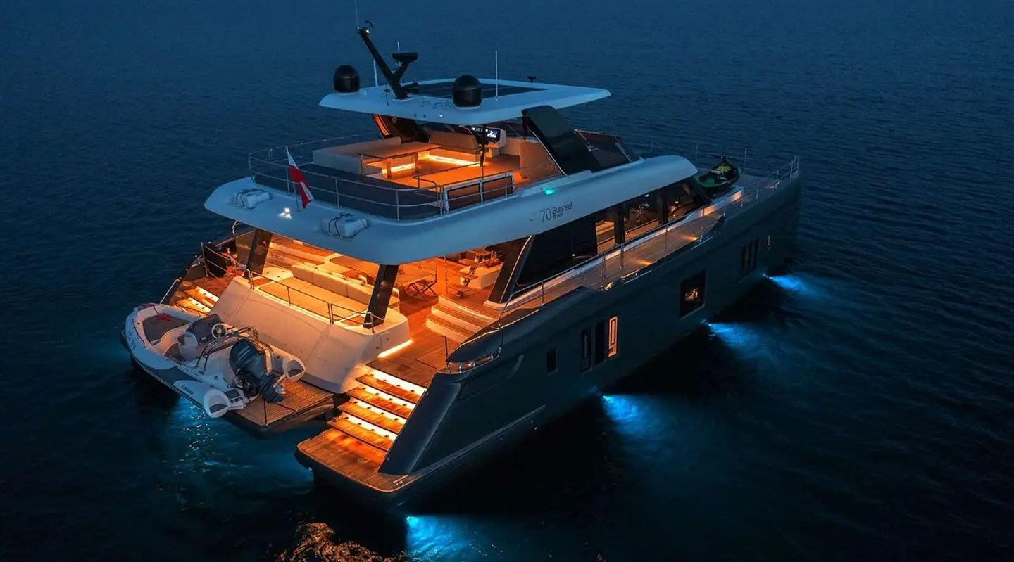 Yacht Alteya at night, illuminated deck lights glow on dark water