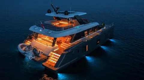 Yacht Alteya at night, illuminated deck lights glow on dark water