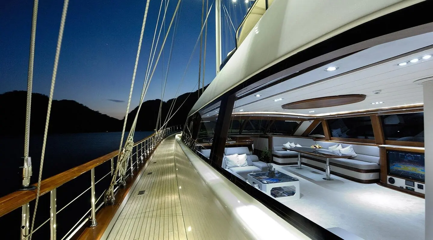 Sunlit luxury gulet deck with polished wood, ropes, and sail rigging at sunset
