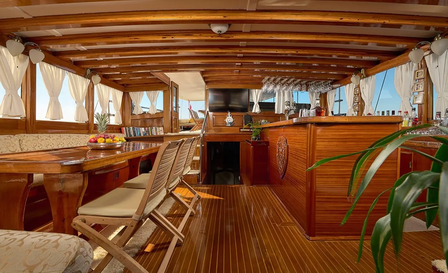 Sunset-lit luxury gulet deck with wooden framing, seating, and helm on Linda