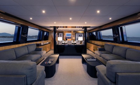 Luxurious motor yacht interior with central dining area and seating, open sea view in the background.