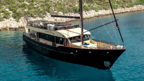 Wide view of Santa Clara yacht anchored in blue water with a wooden deck and cabin