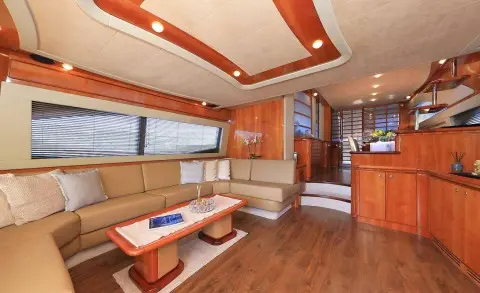 Interior of luxury yacht salon with beige seating, wooden deck, and a coffee table