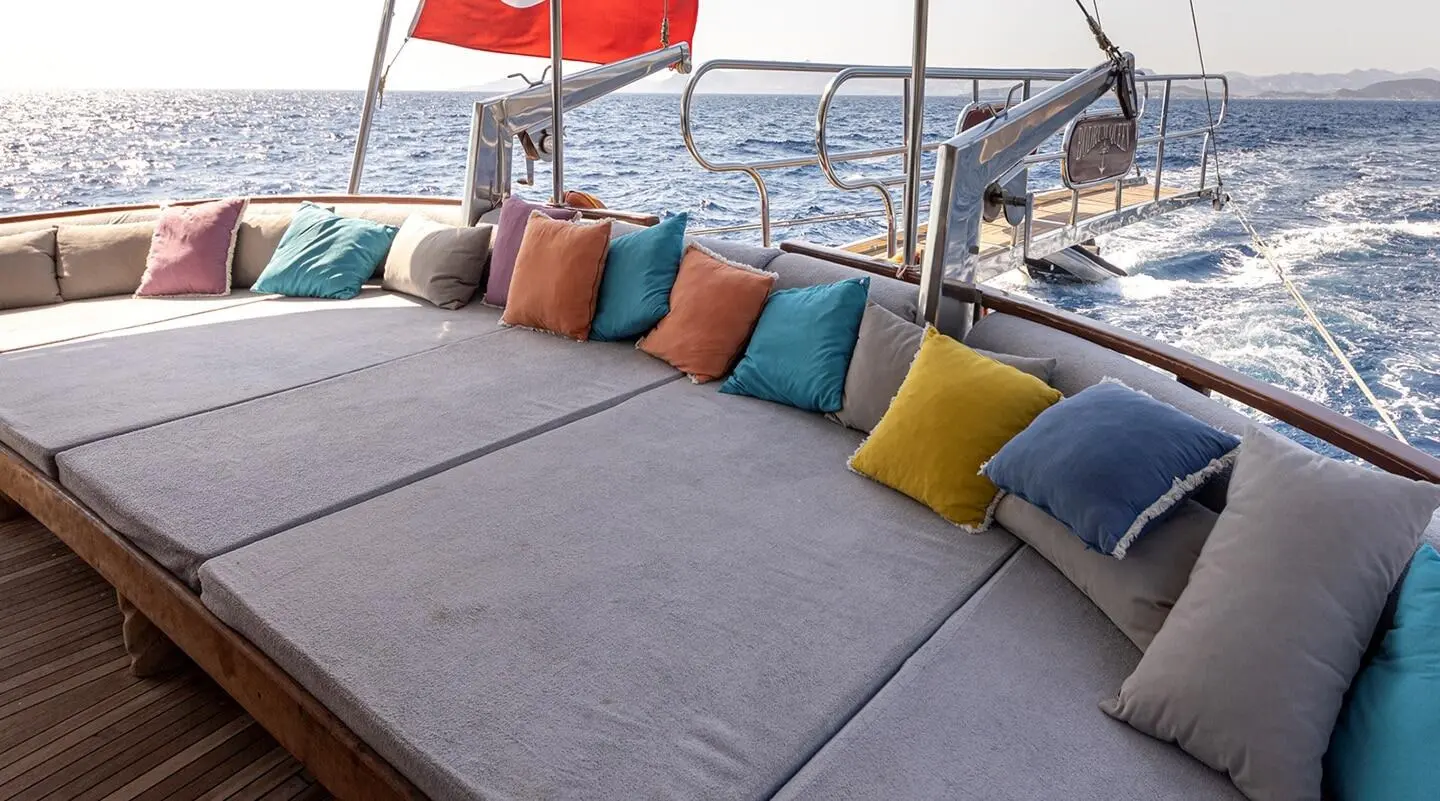 Bodrum Queen yacht deck seating with colorful cushions at sunset on calm sea