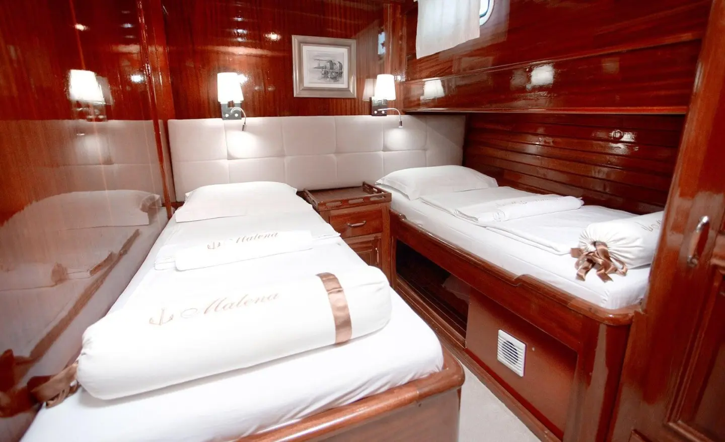 Luxurious yacht interior with multiple white bunks and wood paneling aboard Malena