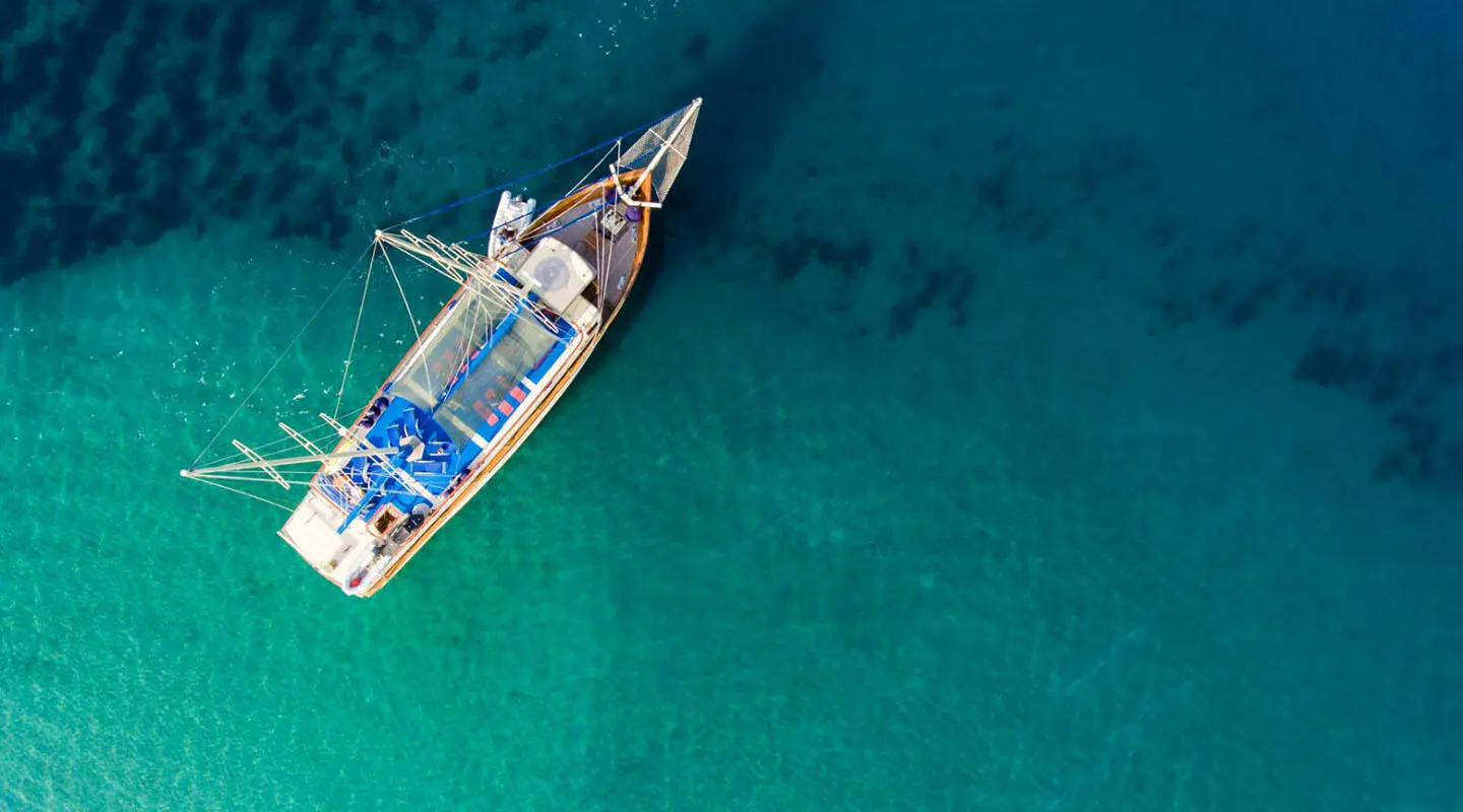 A luxury sailboat with Tajna Mora name anchored in clear turquoise water at dusk