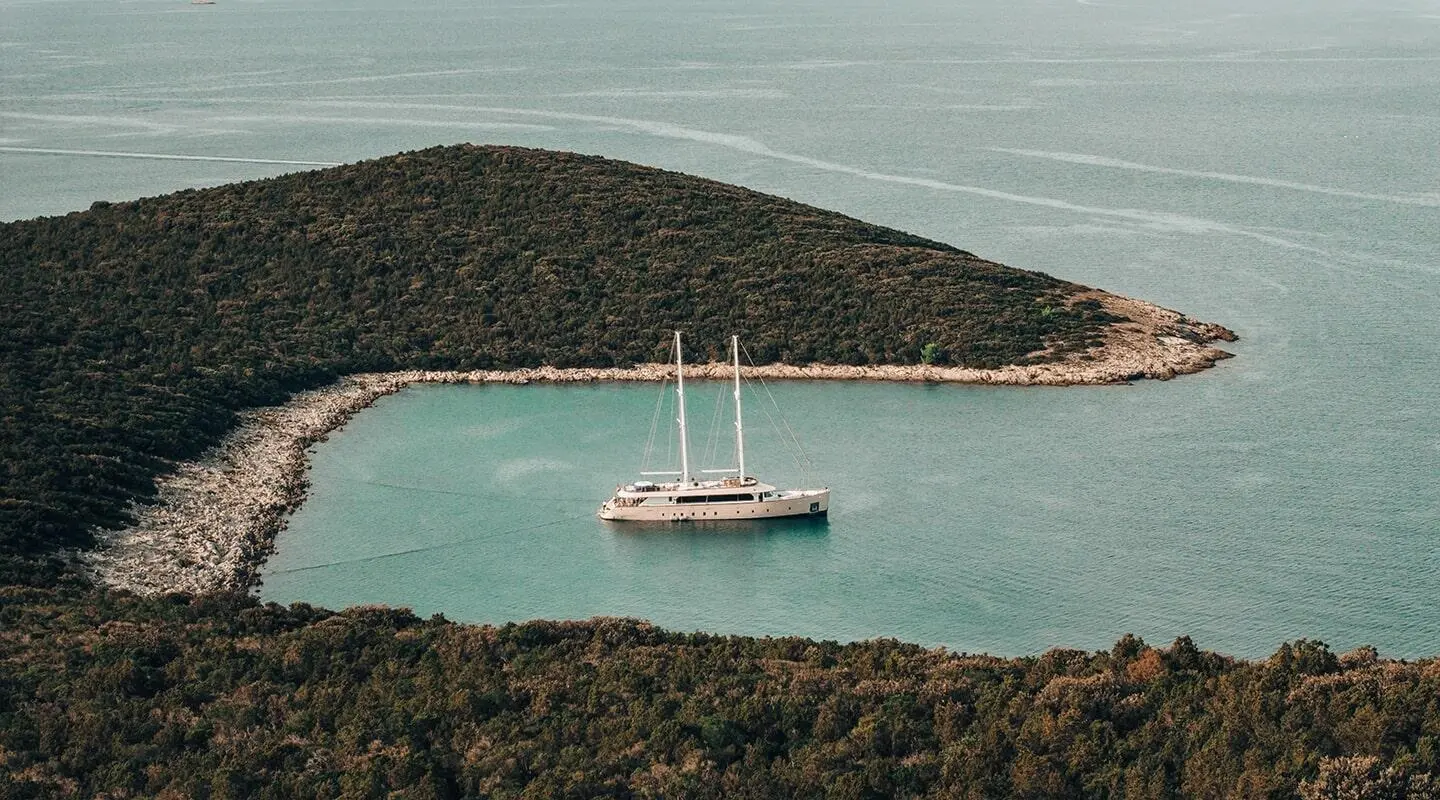 Maxita yacht anchored in a secluded cove with a calm turquoise bay