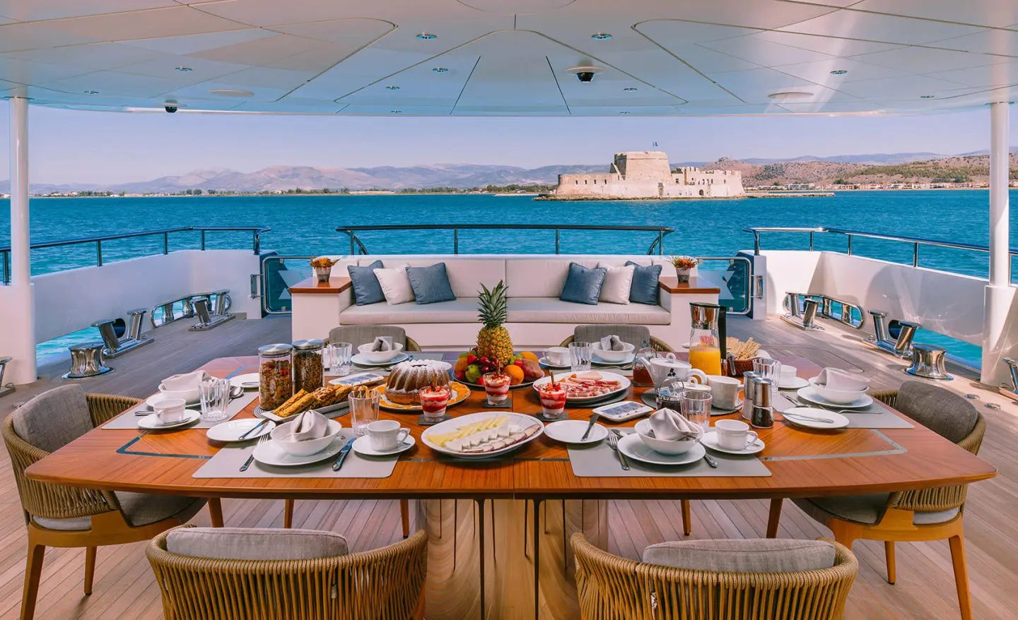 Xana motor yacht aft main deck dining setup with plated meals and sea view