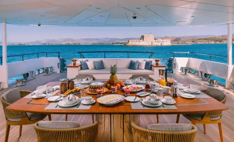 Xana motor yacht aft main deck dining setup with plated meals and sea view