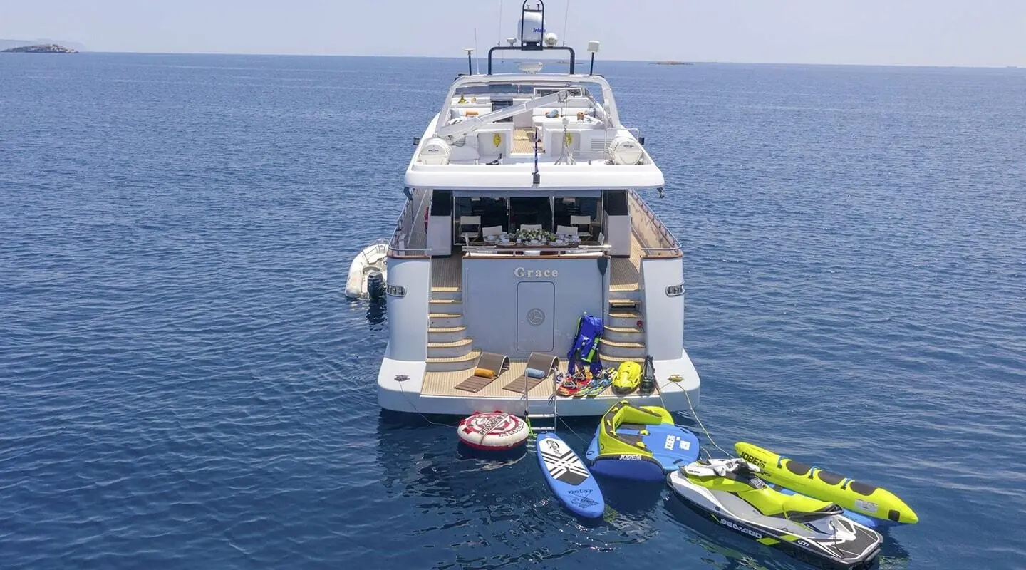 Grace yacht anchored with jet skis nearby in calm blue water