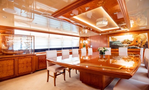 Elegant wooden conference table with white chairs inside a yacht dining area