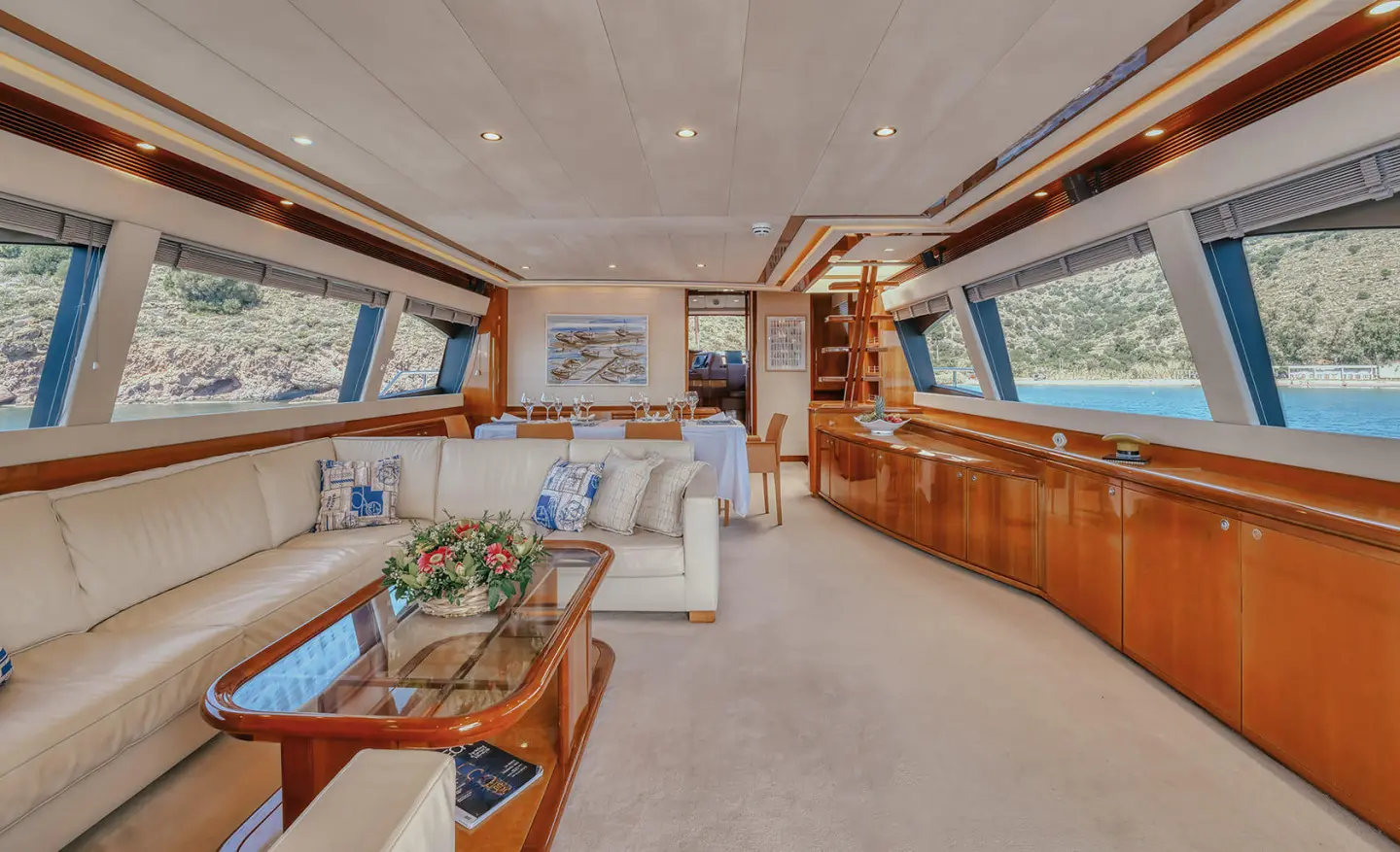 Interior of luxury yacht Lidia showing wooden cabinetry, seating area, and large windows