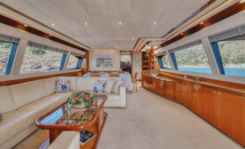 Lidia luxury yacht interior: spacious salon with cream leather sofa, wooden coffee table, dining area, and panoramic windows