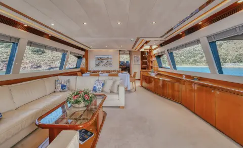 Interior of luxury yacht Lidia showing wooden cabinetry, seating area, and large windows