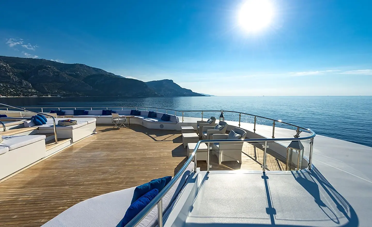Marquise yacht on sunlit deck with navy cushions and sea horizon