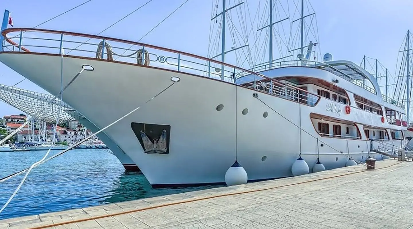 Close-up of a white luxury yacht anchored at a marina with blue water nearby