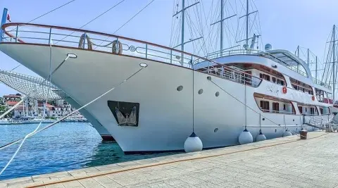 Close-up of a white luxury yacht anchored at a marina with blue water nearby