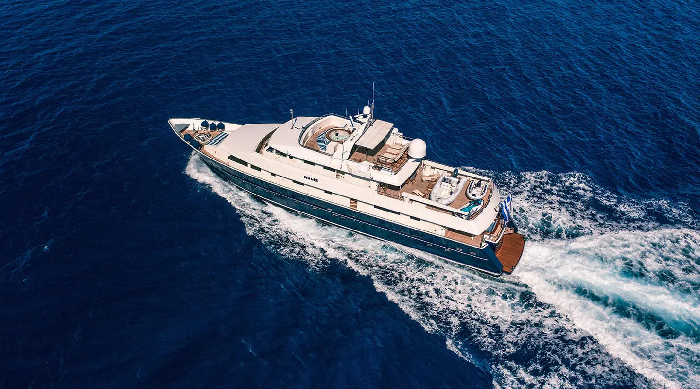 A luxury motor yacht named Magix sails through deep blue water, white wake behind