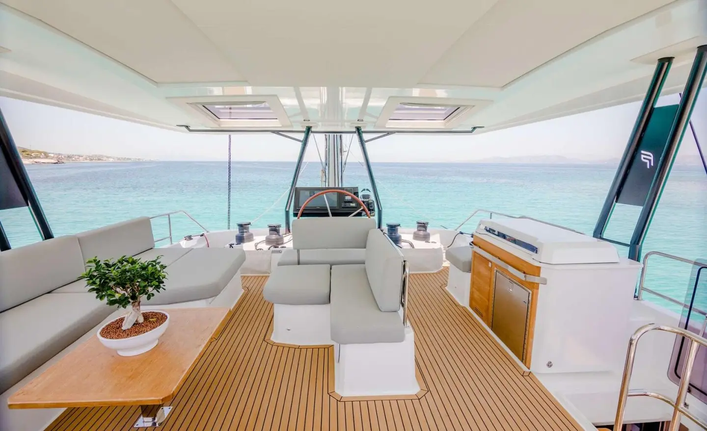 Open deck with seating, helm area and turquoise sea view from the yacht