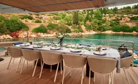 Anetta yacht dining area on deck facing calm turquoise sea at sunset