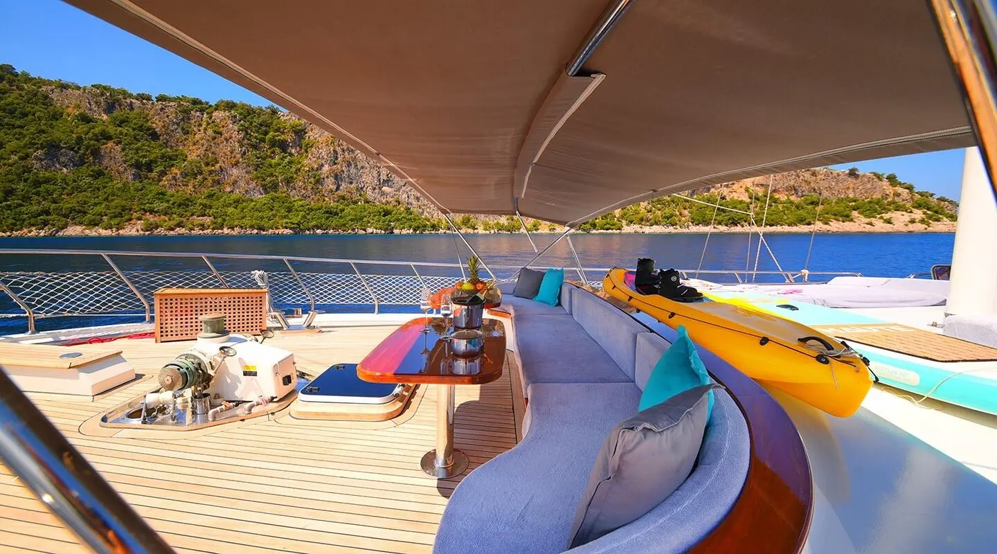 Yacht Maya deck at sunset, sunlit railing, lifebuoys, and sea view