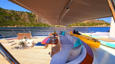 Yacht Maya deck at sunset, sunlit railing, lifebuoys, and sea view