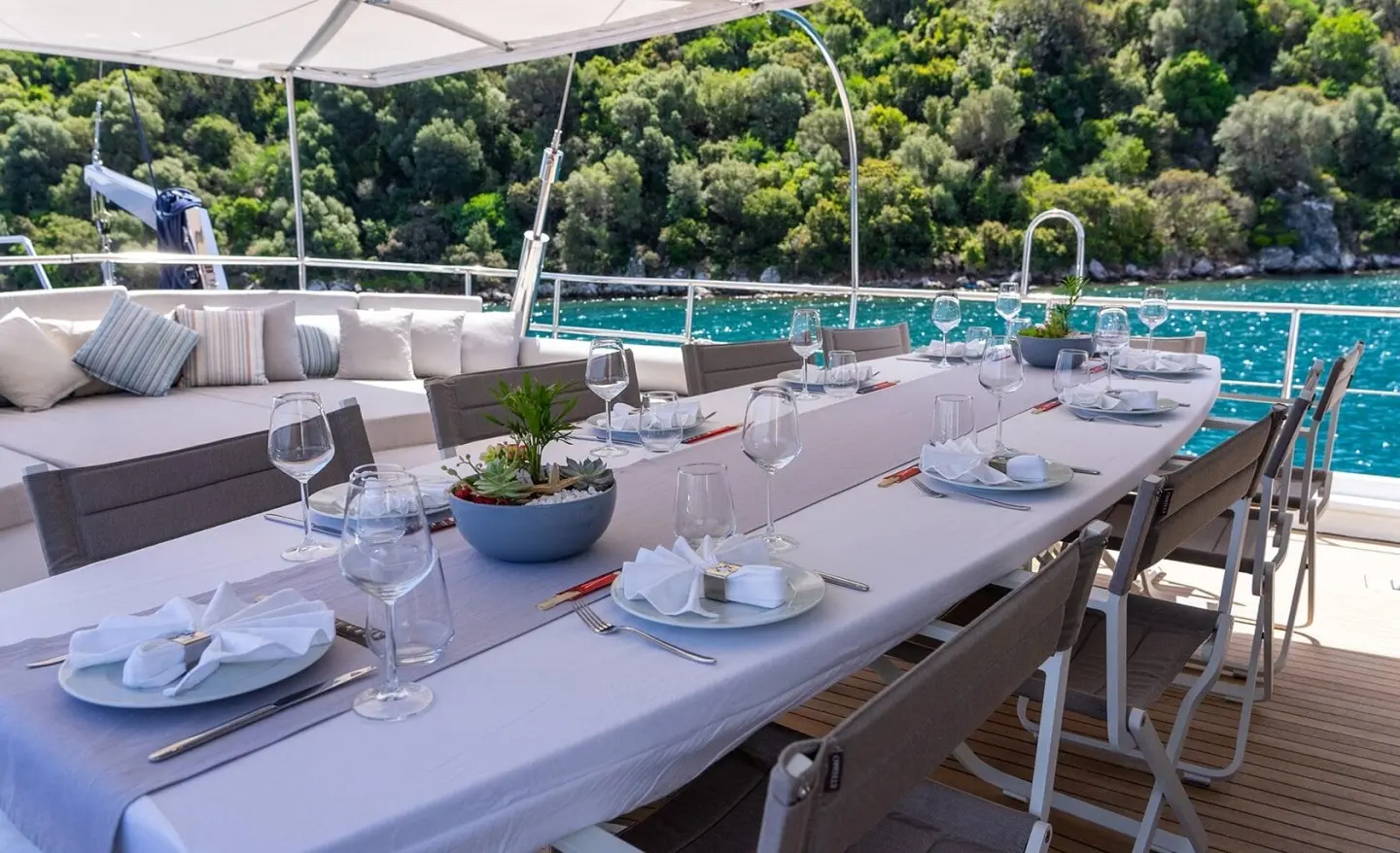 Dining table aboard a yacht at sunset with white tablecloths and chairs