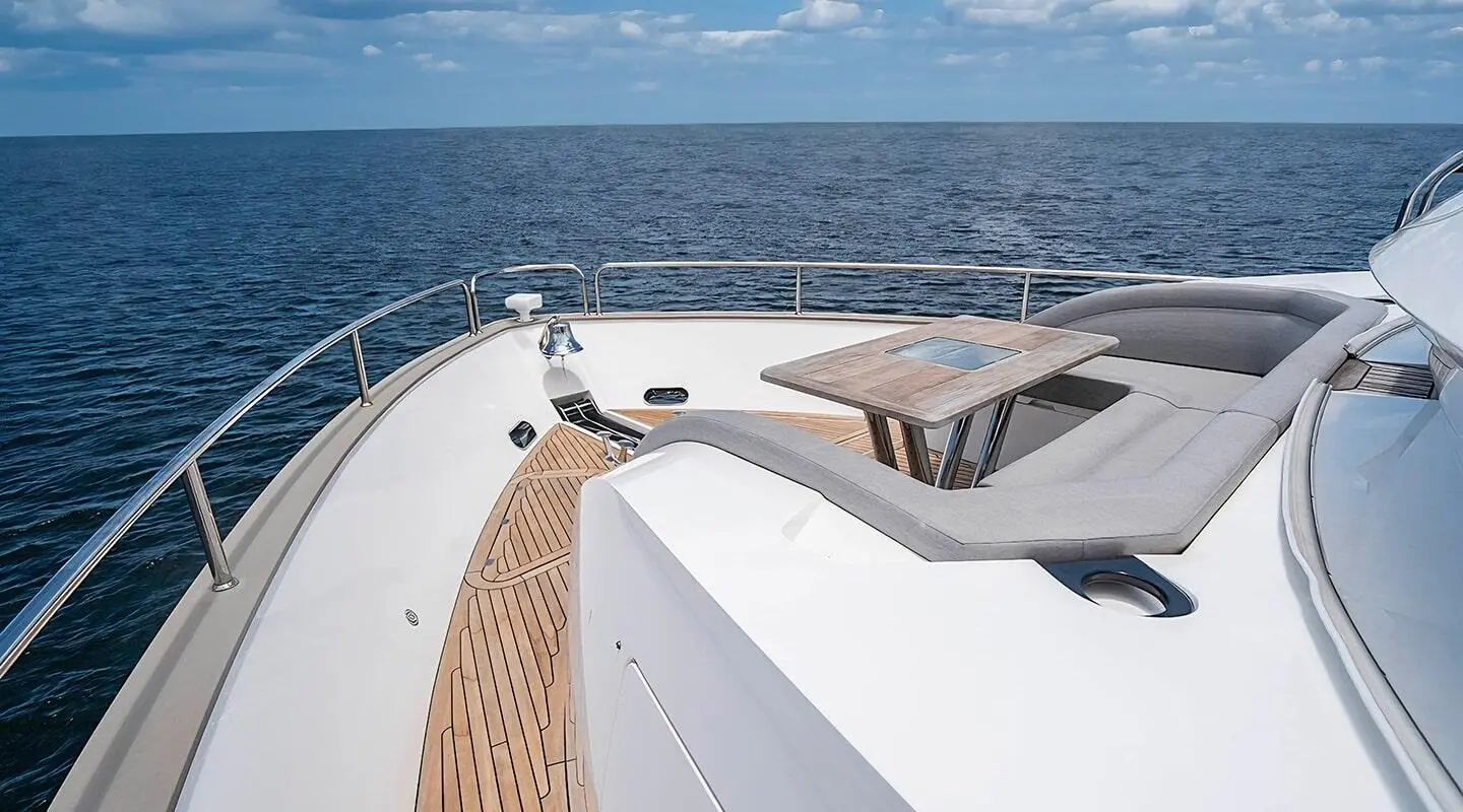 Deck of Quantum yacht with white surface, wooden trim, and blue sea ahead