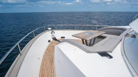 Deck of Quantum yacht with white surface, wooden trim, and blue sea ahead