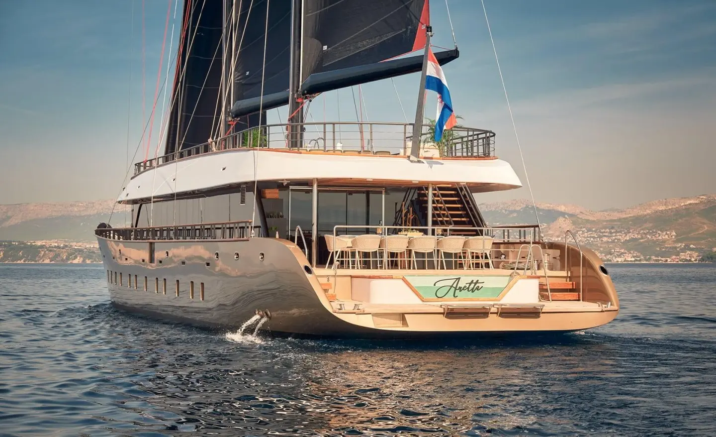 Back view of the Anetta motor yacht anchored in calm water with side deck and wake