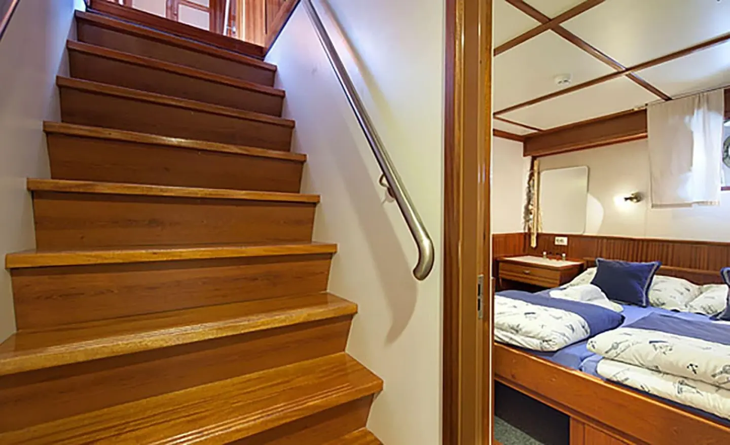 Interior view of a wooden staircase and cabin with a bed visible beyond