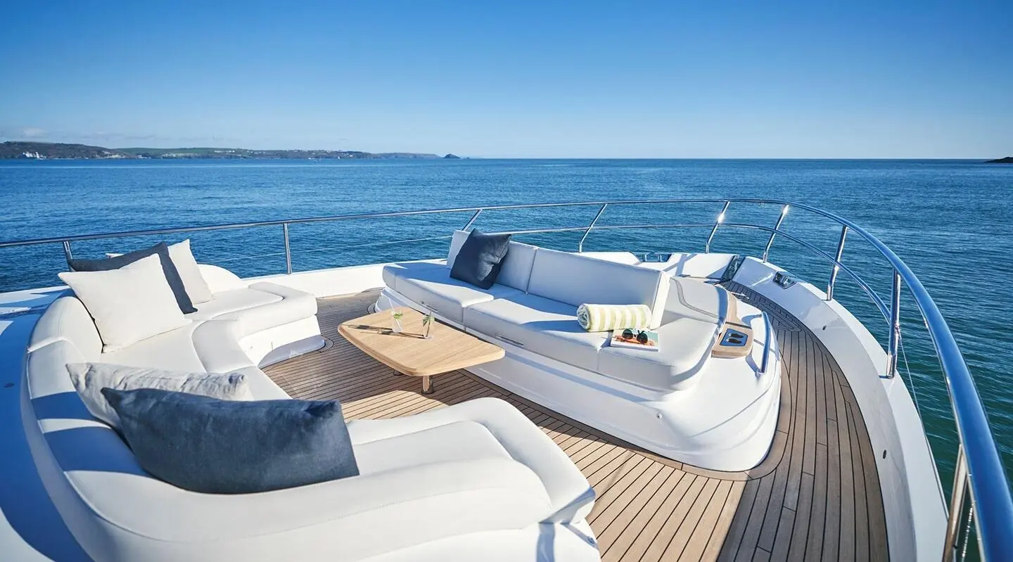 White outdoor seating area on yacht with wooden table and ocean view
