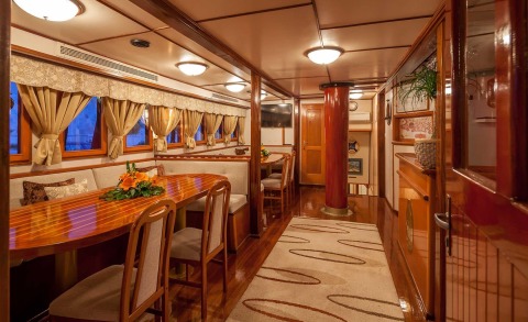 Interior with wooden decor, long dining table and chairs, windows with swag curtains