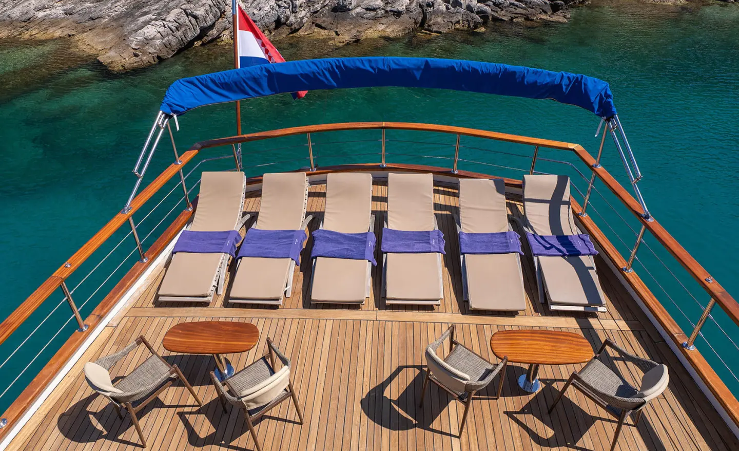 Mendula luxury yacht deck with striped loungers and blue shaded seating at sunset